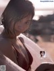 A woman in a red bikini sitting on a beach.