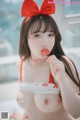 a woman in a red and white bikini eating a piece of cake