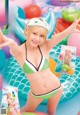 A woman in a green and white bikini posing in a pool.