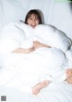 A woman laying in bed with white sheets and pillows.