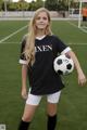 A young woman holding a soccer ball on a soccer field.